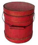 **SOLD** L498 Small 19th century Shaker firkin bearing original dry, red painted surface. Thick walled staved and bentwood construction with wire bail swing handle with wooden handle grip that is secured to the firkin with diamond shaped bail plates. Overlapping finger on all three wooden bands are secured with small copper tacks. Natural patina interior. Measurements: 6 3/8 diameter (Bottom) x 5 7/8 diameter (top) x 6 ½ tall.