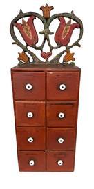 **SOLD** L265 Pennsylvania Folk Art carved and painted eight-drawer Apothecary / Spice Cabinet with original red painted surface with original white porcelain knobs. The top crest features a Folk Art scroll cut out and original polychrome painted heart and tulip motif. The wood is pine with a combination of square head and wire nail construction. Circa 1900-1910. Measurements: Overall height is 26 3/8 tall. Crest is 11 wide x 8 5/8 tall. Case measures 9 ½ wide x 5 5/8 deep x 17 ¾ tall.