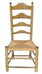 K295 Early 19th century original mustard grain painted Ladder Back Chair featuring curved slats in the back, turned finials on posts and tightly woven rush seat. Measurements: 18 ¾ wide x 39 tall. The seat is 15 ½ tall.