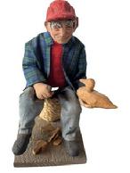 **SOLD** L33 Vintage exceptionally detailed handcrafted sculpture of a Decoy Carver sitting on a spool of rope, whittling a wooden duck decoy. The head, hat, hands and feet appear to be constructed of a type of clay and he is wearing real fabric clothing. Sculpture rests on a wooden base bearing an original sticker on bottom that is signed by artist: H. Hoecker for Allison Hunt Studios - Cape Cod. Measurements: 4 3/8� wide x 5 &frac12;� deep x 8 &frac14;� tall from base to top of hat.  