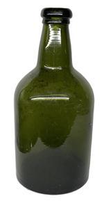 K288 Early Green Glass Wine Bottle featuring bubbled glass, a kicked-in bottom, and an applied rim. Approximate Measurements: 3 7/8 diameter x 8 ¼ tall.