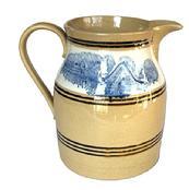 **SOLD** L295 Exceptional and very attractive Mocha decorated yellow ware pitcher with multiple black bands. Dating to the 1800s, this was molded and decorated by master potters and is of the highest quality. The very crisp mocha decoration is blue seaweed on a white background. Several decorative black bands adorn the pitcher both above, and below the mocha decorations. Measurements: 6 bottom diameter x 8 tall.