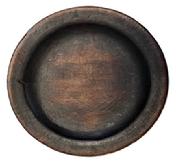 **SOLD** M21 Wooden plate with remnants of red paint on the bottom and dark, natural patina interior. Plate boasts a wide lipped edge and rests on an ever so slightly raised foot. Both sides of this plate show evidence of use. Out of round. Measurements ~ 7 ½ x 7 ¾ diameter x ~3/4-~1 tall, depending on where measured. The lipped edge is ¾ wide.