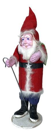 K1885 Tall Santa wearing blue trousers and a red coat and tall pointy hat with white furry trim. His black belt / sash is adorned with a silver star as the "buckle". He is holding a metal shepherd's hook in his right hand and has a green linen sack flung over his left shoulder. Measurements: 11 1/4" tall on a 3 1/4" diameter cardboard base that is stamped "Made in Japan" Distributor: Calvert For Beauty Inc. 6713 26th Street Berwyn ..."