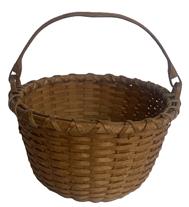 RM1648 Hand woven Swing Handle natural basket - signed "NEWT WASHBURN" on bottom. Tightly woven with double wrapped, double rimmed top with steamed and bent, notched handles that are woven into the sides to secure the swing handle to the basket. Ever so slightly bumped up bottom for weight distribution and added air flow. Excellent condition. Measurements: 8 ¾ x 9 top diameter x 5 ¾ bottom diameter. The sides are 5 tall and overall height with handle is ~9 ½ tall. Newt Washburn (b. 1915) of Vermont is from a well-known line of New England basket makers whose work is highly sought after.