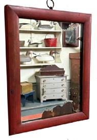 M177 Early 19th century Pennsylvania wooden framed looking glass with the original early silvered mirror encased in a molded edge frame retaining its original red painted surface. Heavy, thick glass with losses to the silvering indicative of age. The wood is pine. The frame is square head nail construction, and a thin-sawed wooden backing is held in place with tiny square head nails. Measurements: 8 ½ wide x 10 ½ tall x ¾ thick. Frame surrounding the looking glass is 7/8 wide