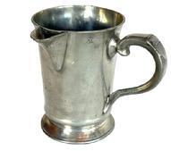 L266C 19th century Pewter Spouted Pitcher - Quart sized - with "ST. JAMES TAVERN" engraved on the bottom. Circa 1837-1850s. This is known as a “One in and two out” or a “You and Me” pitcher. The Innkeeper / Tavern keeper would present this Quart pitcher filled with ale, along with two empty pint-size tankards. The ale was poured from this pitcher into each of the pint size tankards – known as “one for you and one for me.” If additional ale was requested, the Innkeeper / Tavern keeper would refill this pitcher accordingly. Measurements: 4 3/8" diameter base x 6 3/8" tall.