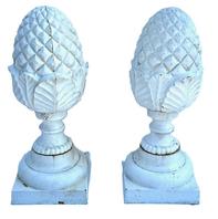 M156 Very early 20th century pair of matching solid cast iron Pineapple finials with geometric diamond shaped details on top and a series of detailed curved leaves and shaped rings below resting on square bases. Surface retains several layers of old white paint. Extremely heavy. Circa 1900-1920s. Approximate measurements: Bases are 8 square x ~20 ¾ tall.