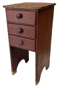 M147 Mid-19th century Pennsylvania three drawer stand featuring dovetailed drawers and half-moon cut out feet in original red painted surface. Unusual configuration. The wood is walnut on the drawer fronts and sides, with secondary wood being white pine. Square head nail construction with mortised/dovetailed drawer stretchers. Circa 1850s. Measurements: 17 ½ wide x 18 deep x 36 ¾ tall. Clearance from bottom drawer to floor is 18 ¼.