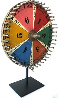 F25 Early 20th century table top Gaming Wheel with six colorful sections and nickeled posts, mounted to a contemporary iron stand. Measurements: 14" dia. Provenance: American Primitive Gallery, New York, New York; A Pennsylvania collection.