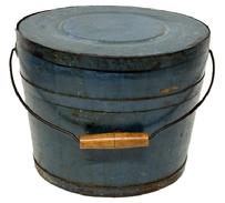 M1144 Identified original blue painted lidded wooden bucket Stamped on bottom Improved and Warranted, by JAMES WHITCHER
.HOOKSET, N H with arched wire bail handle and turned wooden grip. The thick, solid wood lid is rimmed by a ¾ tall metal band secured with hand forged tacks. The interior is old natural patina. Tongue and grooved staved construction held in place with ¾ tall metal bands secured with hand forged tacks. Measurements: 11 ¾ top diameter x 10 - 10 ¼ bottom diameter x 9 ¼ tall.