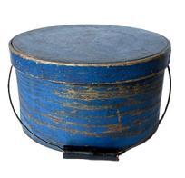 **SOLD** L246 19th century New England Bail Handle Pantry Box with the original old dry dark blue painted surface. The overlapping bentwood sides are secured with small metal tacks. The sides of the Box are fitted with a pair of oval stamped tin handle mounts that secure an arched wire swing handle with wooden hand grip bearing black painted surface. Natural patina interior. Measurements: 11 ½ diameter x 6 3/8 tall.