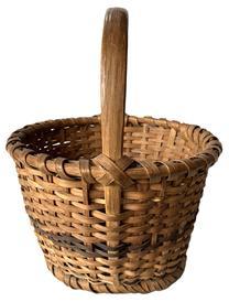 K181 Eastern Shore, Maryland hand woven footed Oak Splint Basket featuring tapered sides resting on single wrapped, steamed and bent footed base. The tall, sturdy, steamed and bent handle is woven into the sides and is secured with tiny tacks into the single wrapped, double rim that matches the footed base. Great natural patina surface with a decorative band of darker woven splints encircling the center of the sides and in the center of the bottom. Measurements: 10 ¾ x 11 ½ diameter across top x 7 tall sides x ~13 tall with handle. The footed base is ~8 ¼ diameter.