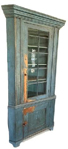 M51 Early 19th century Centre County, Pennsylvania corner cupboard bearing the original blue painted surface. Two-piece construction with one door with 10 windowlites with outstanding wavy, bubbled glass, over a single panel door below resting on a nice cut out base. Beaded edges surround each of the fully mortised and pegged doors. The molded window muntins are also mortised through the door frame. Beautiful, wide cornice molding around top, applied molding along both sides of the front and at waist. The interior retains original blue painted surface and boasts shelves in both sections for added storage. Plate grooves in upper shelves. Wide boards on back. The wood is pine with primarily square head nail construction. Circa 1800 1820s. Measurements: 88 (7 4) tall. Takes a 33 ½ corner at top molding. Case tales a 28 corner.