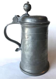 RM1071 Wonderful Pewter Tankard marked “J. N. 1875” on the lid. There is also an embossed pattern creating a ring that encircles the scrolled initials and date on the lid. Inside on the bottom of the Tankard, there are two engraved rings encompassing a fairly prominent touch mark. The touch mark depicts an eagle shield with 2 oval pictures within the shield area. Large Finial on the lid is is in tact. Approximate Measurements: 9” tall x 4 3/8” diameter across bottom.