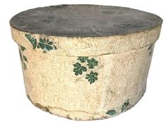 M181 Large, round early 19th century Pennsylvania wallpaper Hat Box / Bandbox. The pasteboard box is covered on the exterior with wallpaper bearing leaves and botanical motifs on an ecru and salmon color patterned background. Interior is covered with several Harrisburg, Pennsylvania newspapers dated 1837. The bottom is covered with newspapers dated 1836 and 1837. Measurements: 15 ¾ top diameter x 8 ¼ tall.
