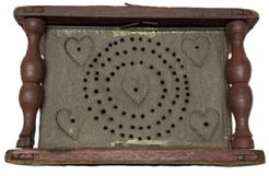 M307 Late 18th to early 19th century Wooden Foot Stove / Foot Warmer bearing original red painted wooden frame, punched tin panels and hand-forged twisted iron bale handle for easy carrying. The fully mortised and pegged wooden frame with turned post corners secures the tin heating chamber that features great folk art punched tin panels bearing punched heart decoration. Retains its original removable rectangular sheet metal cup inside to hold the coal / ashes. Measurements: 7 5/8 x 9 x 5 ¾ tall.