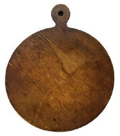 M175 19th century Pennsylvania round wooden cutting board with lollipop shaped top bearing remnants of blue painted edges and natural patina surface on each side with evidence of chop / slice marks from years of use. The shaped top has a hole for hanging purposes. The wood is pine. Measurements: 19 5/8 long x 16 5/8 wide x ¾ thick.