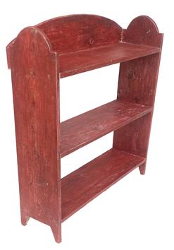 RM1097 Eastern Shore, Maryland bucket bench in original red paint with wonderful tombstone shaped ends, rounded gallery-style backboard and cut out feet. Combination of wire nail and square nail construction. Circa 1890 - 1910. Measurements: 33 5/8” w x 36 5/8” tall (back) x 10 ¼” deep (shelves are 9 ½” deep)