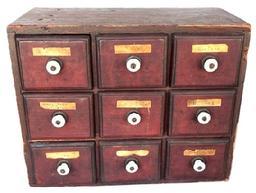 L359 19th century Pennsylvania nine-drawer spice chest / apothecary bearing original red painted surface with molded edged drawers bearing original porcelain knobs and original paper labels. Tiny square head nail construction. The wood is pine . Circa 1840-1850s. Measurements: 14 wide x 7 deep x 11 tall.