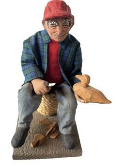 **SOLD** L33 Vintage exceptionally detailed handcrafted sculpture of a Decoy Carver sitting on a spool of rope, whittling a wooden duck decoy. The head, hat, hands and feet appear to be constructed of a type of clay and he is wearing real fabric clothing. Sculpture rests on a wooden base bearing an original sticker on bottom that is signed by artist: H. Hoecker for Allison Hunt Studios - Cape Cod. Measurements: 4 3/8� wide x 5 &frac12;� deep x 8 &frac14;� tall from base to top of hat.  