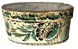 K253 19th century Pennsylvania small oval wallpaper Hat Box or Bandbox. The outside of the oval pasteboard box is covered in wallpaper bearing a floral pattern in greens, reds, black, browns and pale blues. The interior and bottom of this box is uncovered. Measurements: 7 wide x 5 deep x 3 ¼ tall.