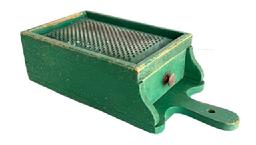 RM1630 Early wooden box grater with drawer retaining its original dry green painted surface. Grater boasts a hand punched perforated, heavy metal grater surface over a sturdy full length functional drawer that slides in and out without problems and has a small knob for easy opening/closing. A cut-out handle with hole for hanging purposes and shaped ends by the drawer opening add to the visual appeal to this functional kitchen necessity. Maker attached a 5/8 wide strip of wood across the back to slightly elevate the upper end of the grater when in use. Great wear indicative of age and use. The wood is pine with small wire nail construction. Circa 1880s 1900. Measurements:15 5/8 long x7 1/8 wide x 4 tall.