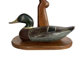 RM1101 James Holly Mallard decoy lamp with wooden gun stock handle on an oval wooden base. Base measures 16” wide x 10 ¼” deep. Overall height is 28” to top of finial.