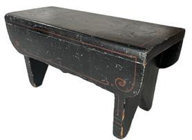 K1823 Pennsylvania paint decorated wooden foot stool retaining black painted surface with heart decoration on the top and simple red, blue and green pinstriping accents on the aprons and each of the legs and feet. The drop aprons on each side boast nicely rounded corners and pinstripe decoration. Bootjack cut out feet. The wood is pine. Square head nail construction. Circa 1840-1850s. Measurements: 13 long x 5 ½ wide x 6 5/8 tall.