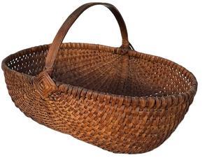 **SOLD** K1844 Oval shaped Melon Basket of ribbed and woven oak splint construction with natural finish boasting the "Eye of the Wind God" on each side of the handle. Tightly woven. Approximate Measurements: 15 ¼ long x 10 ¾ wide x 10 tall at handle. The sides are 5 ¼ tall.