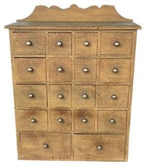 J126 Late 19th century Pennsylvania original Mustard painted apothecary / spice cabinet featuring an unusual 18 drawer layout with brass pulls. The drawer stretchers are mortised into the ends. A decorative cut out backsplash adorns the back while a chamfered edge surrounds the other three sides of the top. Measurements: 21 wide x 8 ½ deep x 27 tall (center of back). The front measures 24 tall.