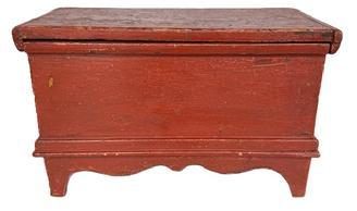 L516 19th century New England miniature blanket chest with old red painted surface featuring tall cut out feet, decorative apron and applied moldings. The wood is white pine with square head nail construction. Natural patina interior. Circa 1860s-1880s. Measurements: 18 ¾ wide x 9 ½ deep x 11 ¾ tall.