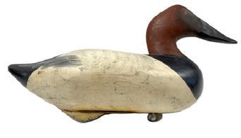 L493 Canvasback Hen Decoy - Signed and dated on bottom "R. Madison Mitchell 1954". Original weight and ring are intact on bottom of decoy.  Imprinted metal tag identifying a presumed former owner, �J. W. Mowery � 435 N. Mary Street - Lancaster PA� also remains intact on bottom. Original surface with early age crack to body. Approximate measurements: 15� long x 6 &frac12;� wide.