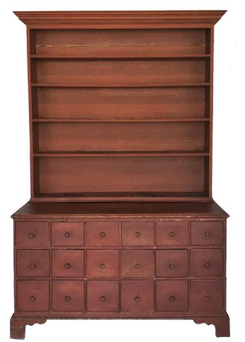 E224 Early 19th century Pennslyvania Apothecary stepback Cupboard two-piece construction, upper case with applied molded cornice, above four fixed shelves, lower case with 18 dovetailed deep drawers, raised on simple bracket feet with cut-outs. Retains a red -painted surface. First half 19th century. 82" H, 57" W, 24" D..