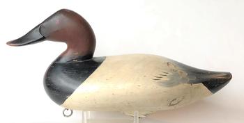 RM1090 Canvasback Drake carved by Charlie Joiner of Chestertown, Maryland. Branded (E.W.) on bottom. Wide bill carving and painted eyes. CONDITION: A few very minor dents, otherwise excellent and original. Measures 16” long.