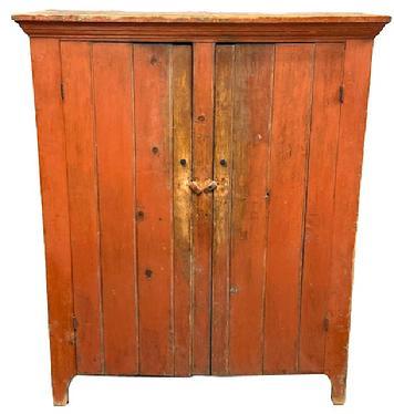 L192 Nice, early 19th century Lehigh Valley, Pennsylvania two door storage cupboard bearing its original bittersweet red painted surface. Cupboard features a dovetailed case with applied cornice molding and cut out feet. Natural patina interior with shelves for added storage options. The wood is pine with square head nail construction. Circa 1840s. Measurements: 49 &frac12;� wide x 19 &frac34;� deep x 59 &frac14;� tall.   