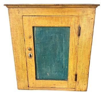 L240 Small 19th century hanging cupboard boasting original mustard painted surface with original blue painted panel door. Applied molding surrounds the top. The case is dovetailed, and the door is fully mortised and wooden pegged construction. The internal shelf is mortised into the sides. The wood is pine. Circa 1850s. Measurements: 19” wide x 9 ¼” deep x 20 ½” tall.
