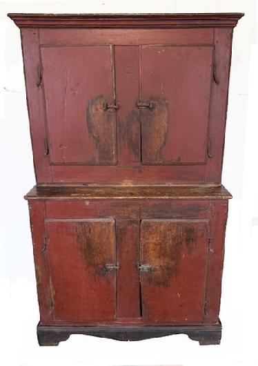 **SOLD** L506 Early 18th century New England original red painted stepback cupboard with applied bracket base bearing original black painted surface. Original rat tail hinges and hardware. Molded edges surround each of the doors. Interior has a dirty dish shelf and bears natural patina surface. The wood is pine with rosehead nail construction. Circa 1720s-1740s. Measurements: 44 ¾ wide x 19 ¼ deep x 71 ½ tall.