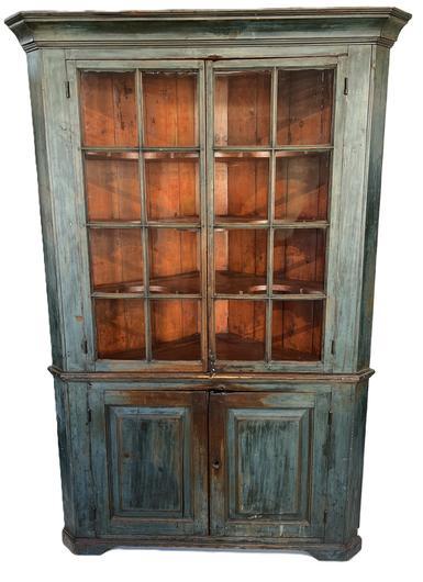 L19 Exceptional 19th century Pennsylvania one piece blue painted corner cupboard with two, 8-windowlite glass doors up top over two raised paneled doors below. Glass doors, featuring the original wavy glass, open to reveal butterfly shelves and a beautiful bittersweet painted interior. Wonderful, applied molding surrounds the top and cupboard rests on an applied cut out base. All doors are fully mortised and pegged. Case is square head nail construction. Measurements: 53� x 36� x 80 &frac12;� tall. 