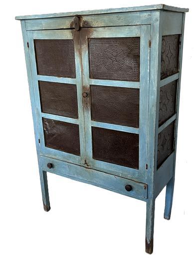 K1670 Late 19th century original blue painted Pie Safe with 12 punched tin panels.  The tins on the front have stars and on the sides the tins have stars inside circles. Two doors over one drawer configuration, resting on tall legs. Stenciled maker�s mark on back reads �G & SON�. Measurements:  40 &frac12;� wide x 17 &frac12;� deep x 60 &frac34;� tall. 