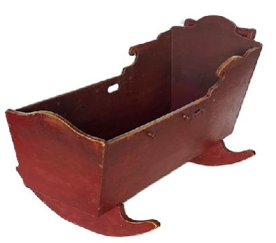 L87 19th century rocking cradle bearing original red painted surface. Beautiful handmade dovetail construction with cut out handles on each side and an applied round handle at the top. The wood is pine. Circa 1840  1860s. Overall measurements: 39 ½ long x 23 ½ wide. Cradle box measures 37 ¾ long x 15 wide. 