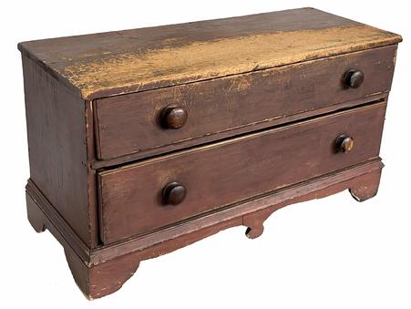 H920 New England original red painted low chest featuring two dovetailed drawers and an applied bracket base boasting a beautiful cut out design. Nice, dry painted surface with great wear from years of use as a bench. The wood is pine. Measurements: 40 ½ wide x 16 ½ deep x 22 tall.