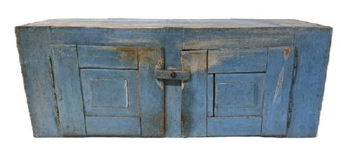 **SOLD** M267 19th century hanging cupboard bearing two raised panel doors and original blue painted surface. The wood is pine with two fully mortised raised panel doors, and dovetailed case with square head and small wire nail construction. Original turn knob secures the doors closed. Natural patina interior. Removeable shelf (later addition) inside the left door, whereas the right contains an open interior. From an Estate in Chambersburg, PA. Measurements: 44 ½ wide x 16 deep x 17 tall.