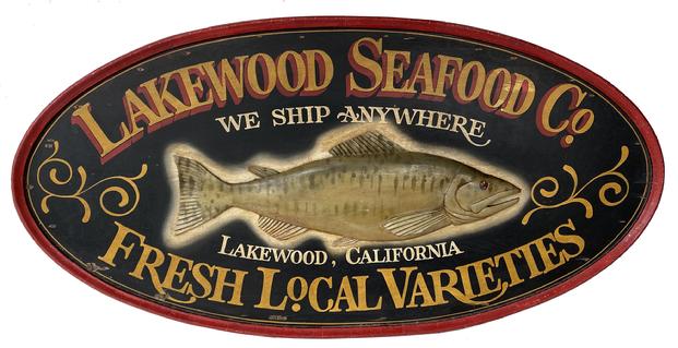 F151 Early 20th century beautiful wooden Double Sided Seafood Co. Hanging Wood Advertising Sign. Large oval double sided sign centered with a relief carved fish and reads "Lakewood Seafood Co., We Ship Anywhere, Fresh Local Varieties, Lakewood, California". Very nice overall condition, minor paint flaking, missing some of the raised molding on the left edge of one side Measurements are: 30" high x 60" wide x 2 1/4" deep