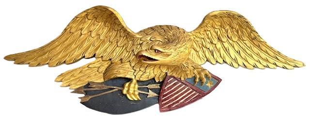 L415 Great piece of Americana Folk Art! This wooden hand carved and painted wall mount depicting a large Eagle with Shield boasts deeply carved details to the feathers, feet, eyes and beak. Original gold gild, red, blue, white and black polychrome painted surface. The Eagle is clutching several arrows in its right talons and a dimensional carved shield stars and bars in its left talons. Measurements: 43 &frac34;� wingspan x 5 &frac12;� deep x ~15 &frac14;� tall. 