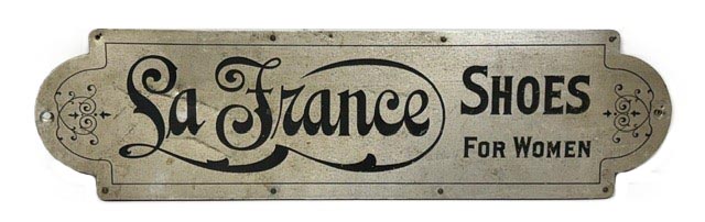 M1153 Early 20th century Trade sign advertising “La France Shoes for Women”. Metal front on a wooden framed back. La France Shoe Company was established in Lynn, Massachusetts in the early 20<sup>th</sup> century and became a national brand that was iconic between 1900 and the 1920s for their elegant, tailored women's shoes with 'comfort arch'.